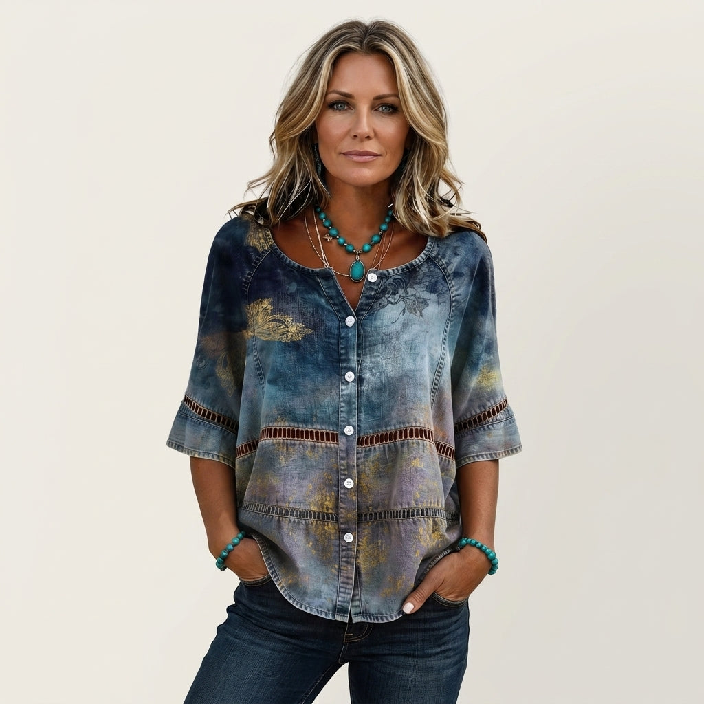 Mujer con blusa efecto vaquero en azul y lavanda con flores doradas, calados y manga tres cuartos